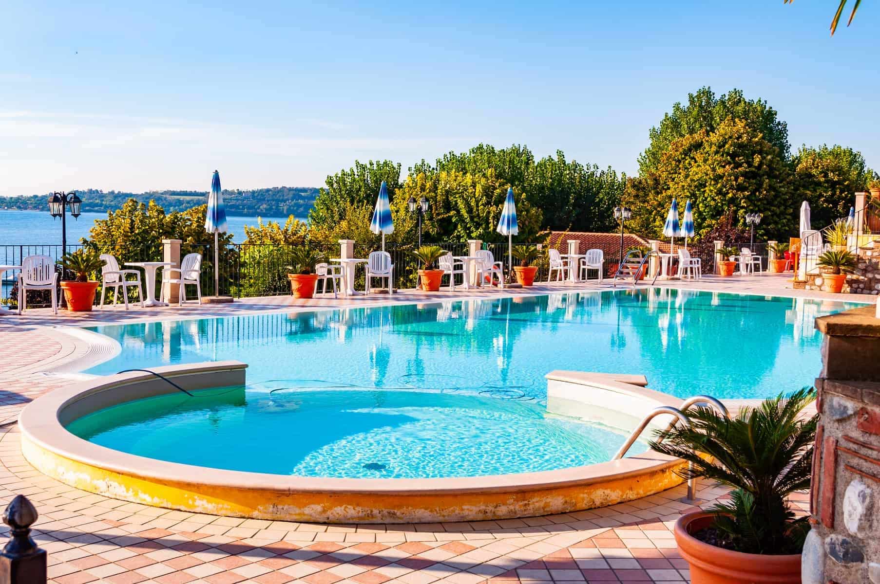 Camping La Ca, Garda Lake, Lombardy, Italy - September 12, 2019: Outdoor pool with vibrant crystal water, parasols and deck chairs located on the coast of Garda lake in amazing La Ca camping in Italy