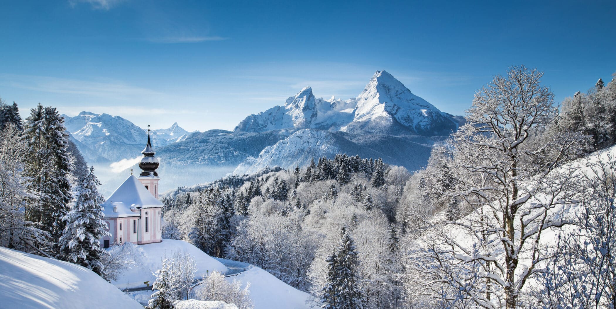 Panoramic view of beautiful winter landscape in the Bavarian Alps with pilgrimage church of Maria Gern and famous Watzmann massif in the background, Nationalpark Berchtesgadener Land, Bavaria, Germany.