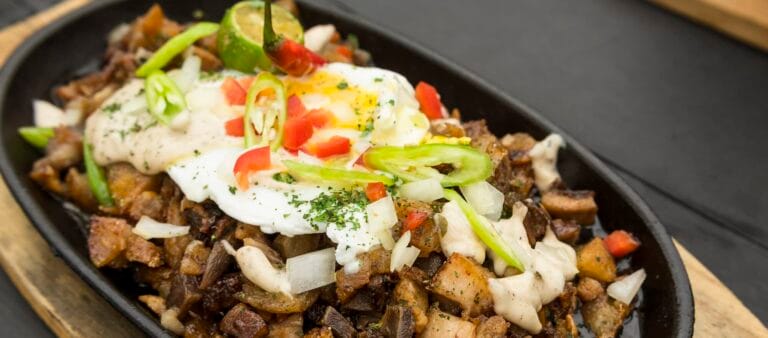 Freshly cooked Pork Sisig with egg, onions and chilies. A popular Filipino dish.